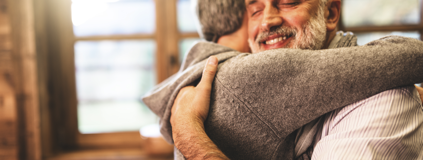 Two men embrace with a smile