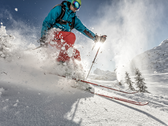 Person skiing down hill with powder snow flying around them