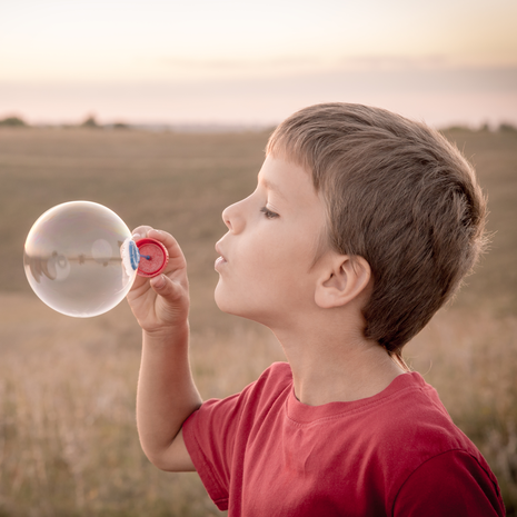 boy blowing up the soap bubbles