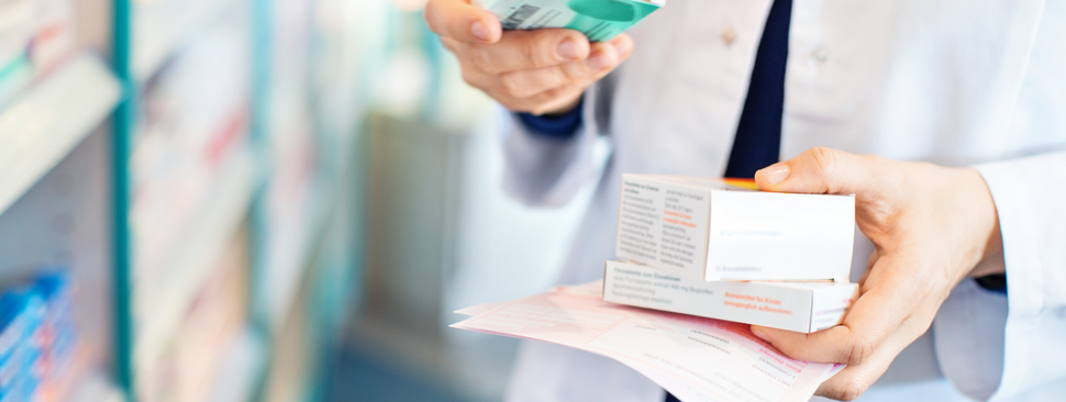 Closeup of pharmacist's hands taking medicines from shelf at the pharmacy