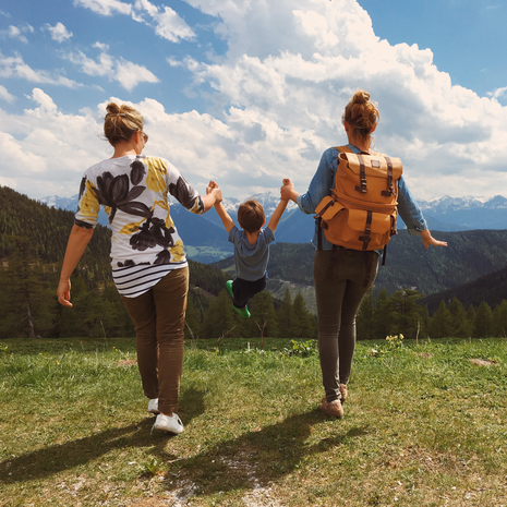 Two women swinging their child between them while on a hike