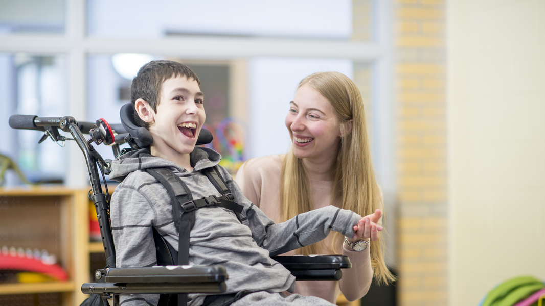 Smiling boy in wheelchair with young woman
