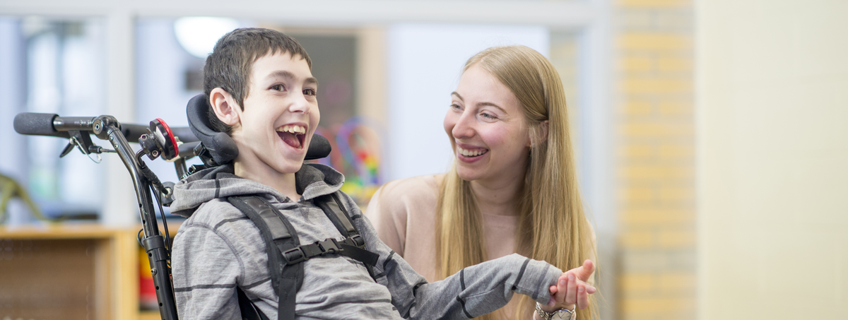 Smiling boy in wheelchair with young woman