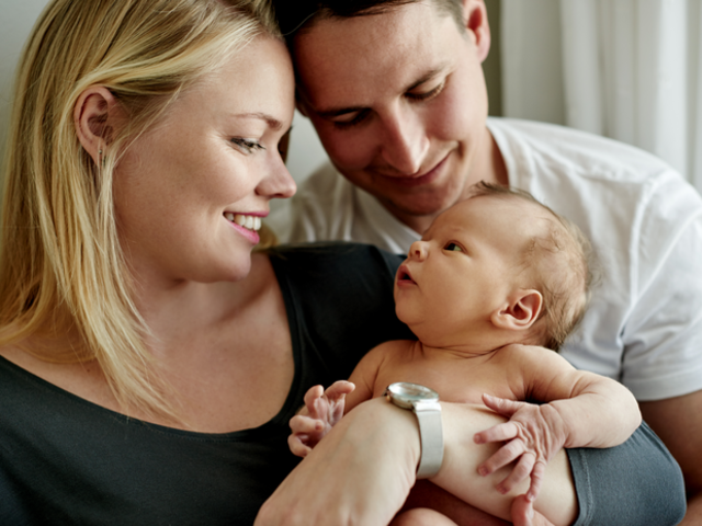 A man and woman gazing at a newborn
