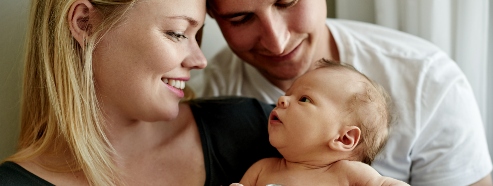 A man and woman gazing at a newborn