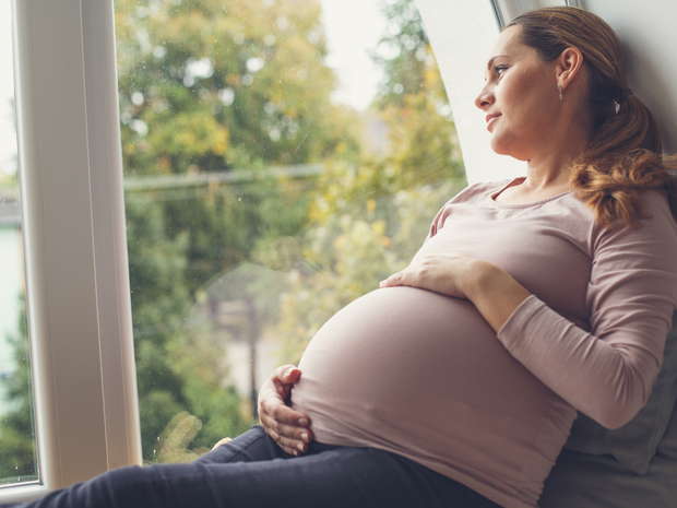 Pregnant woman looking out of her window