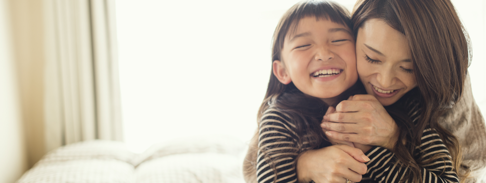 Mother hugs daughter as they both smile