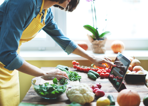 A person uses a tablet while cooking in a kitchen