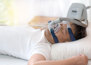 A man sleeps while wearing a CPAP device