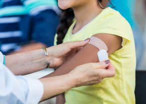 A child has a bandaid on after a flu shot
