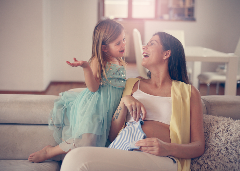A pregnant mother talks to her daughter with a smile