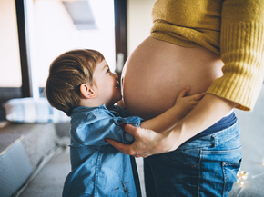 Young boy embracing pregnant mother
