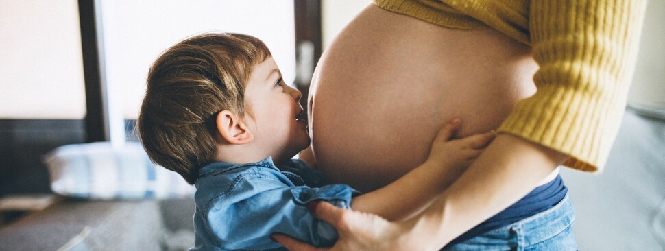 Pregnant mother with young boy embrace eachother
