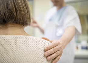 A doctor rests his hand on the shoulder of a patient