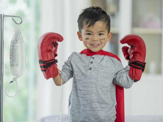 Smiling child with IV and boxing gloves