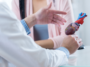 Cardiologist gestures while discussing diagnosis with a patient.