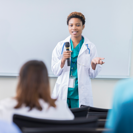 Young female physician speaks to a group of nurses at a conference