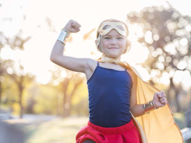 Young girl smiling with cape on.