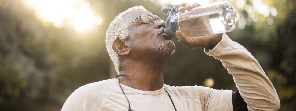 Elderly active male drinking water from bottle