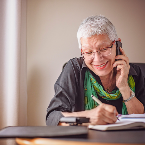Woman on phone writing on paper