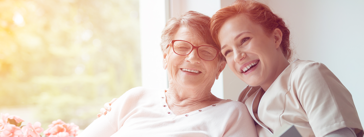 Two women laugh happily while seated on a couch