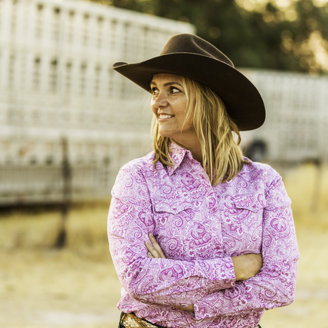 photo of a strong woman with trailers in the background, ready for rodeo