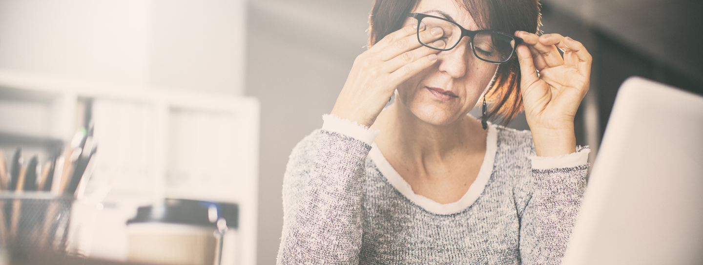 A woman holds her glasses as she rubs one of her eyes