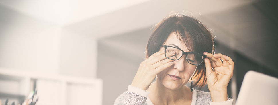 A woman holds her glasses as she rubs one of her eyes