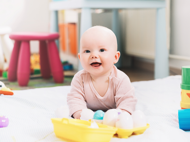 Infant playing with plastic egg toys.