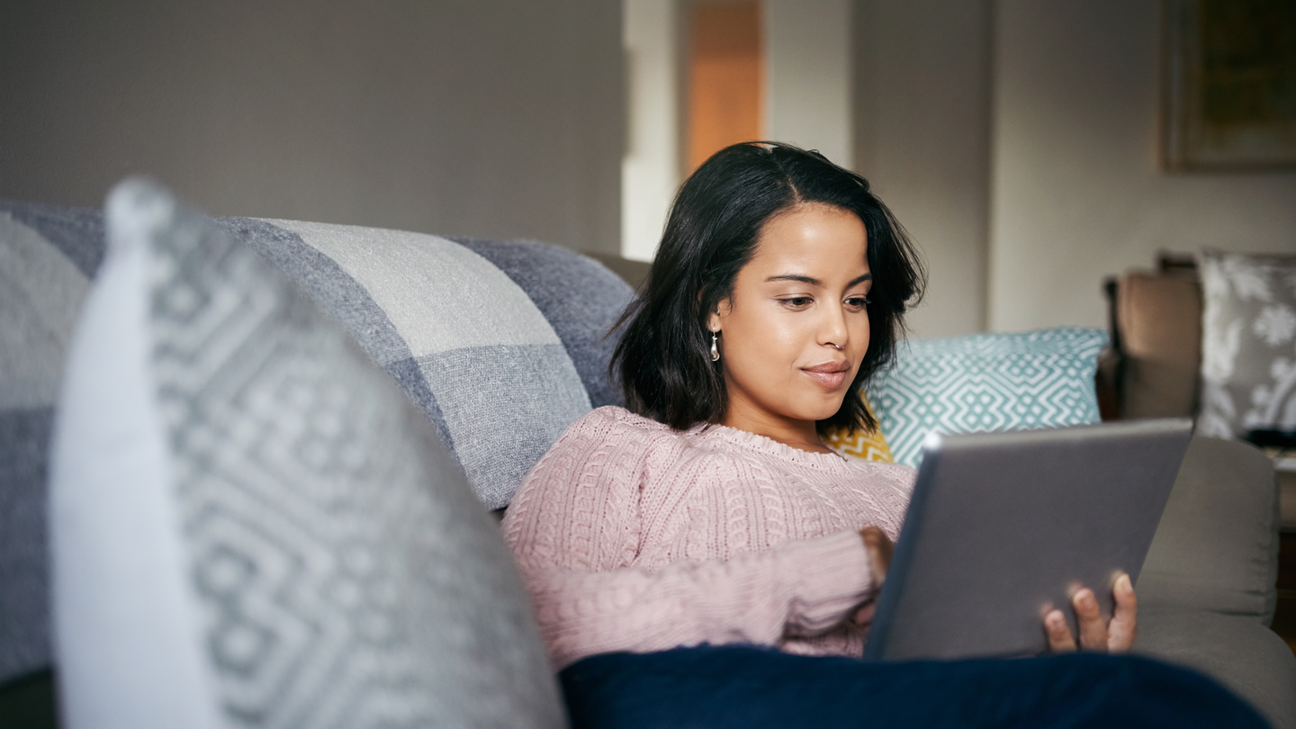 Woman sitting on a couch with tablet. 