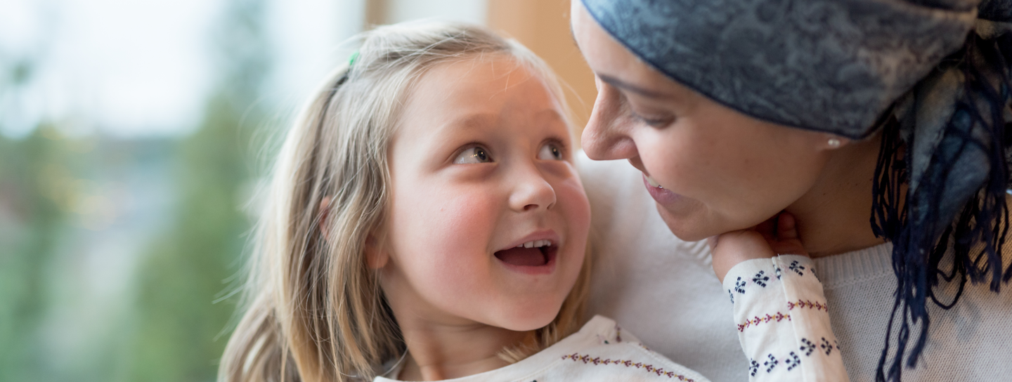 A woman wearing a head scarf smiles at a child sitting on her lap