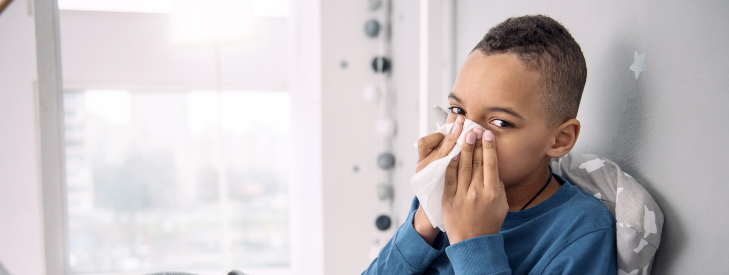 young boy with a cold blowing his nose