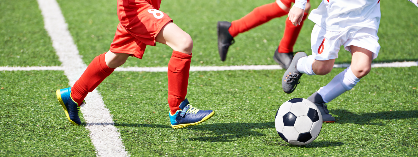 Child soccer players and ball on football field 