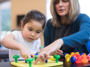 young girl works on motor skills with a therapist