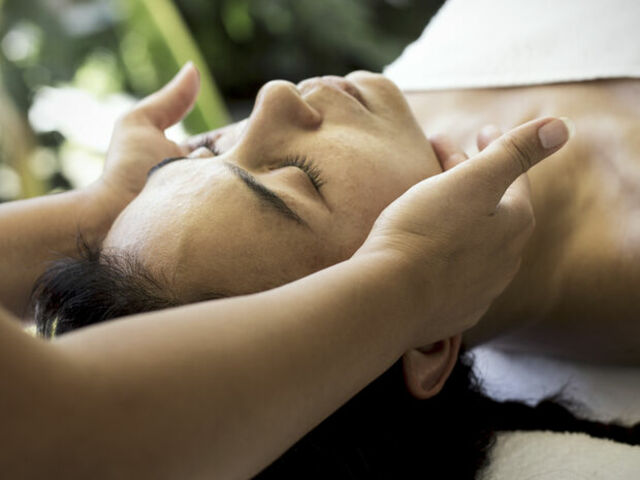 Woman on table with gentle hands on her jaw.