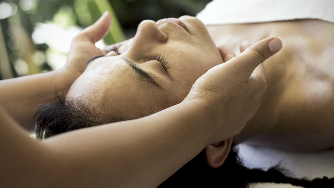 Woman on table with gentle hands on her jaw.