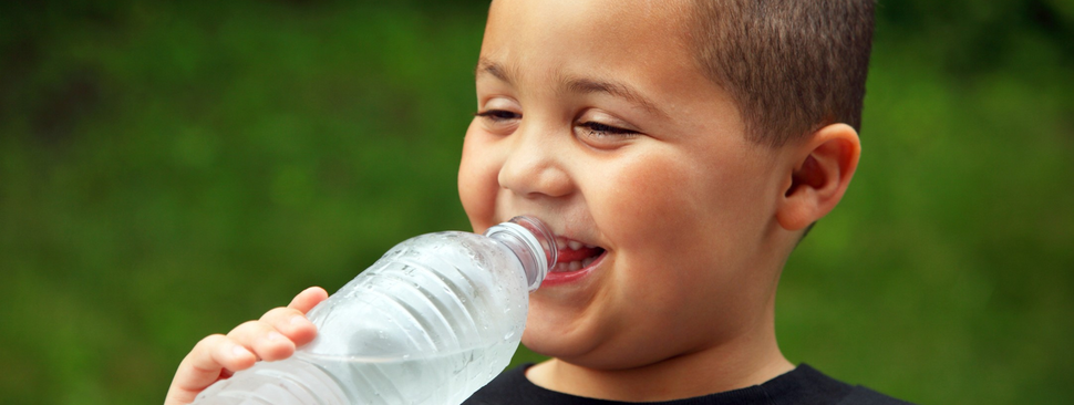 A boy drinking water outdoors