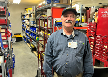 Man wearing grey hat smiles in front of shelving