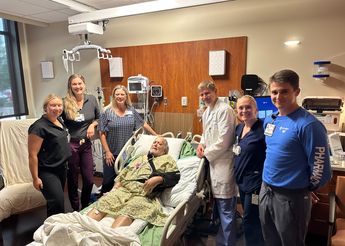 Medical staff surround man in hospital bed