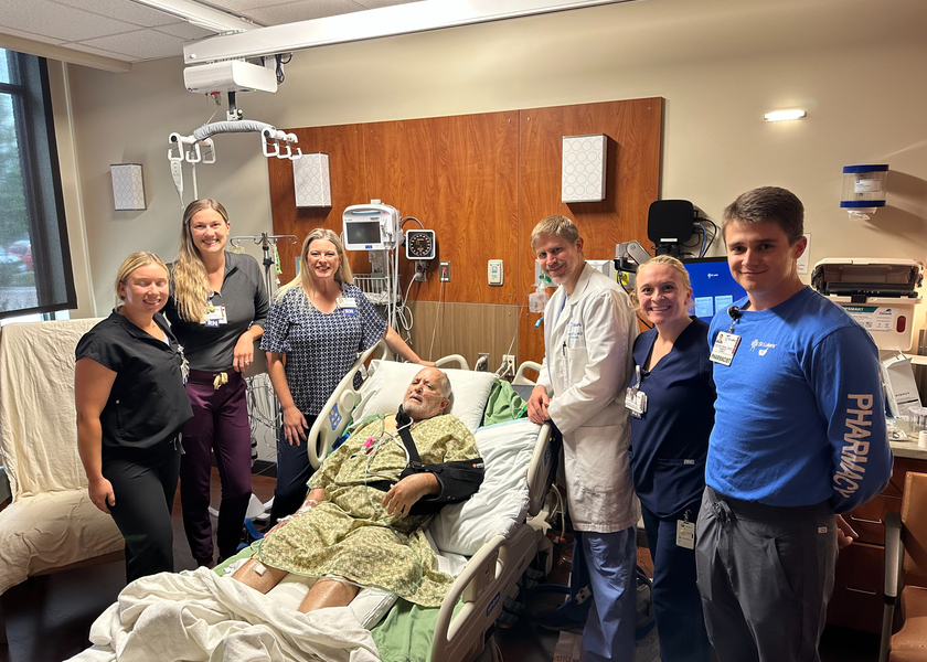 Medical staff surround man in hospital bed