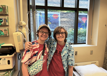 Two people smiling in front of a window