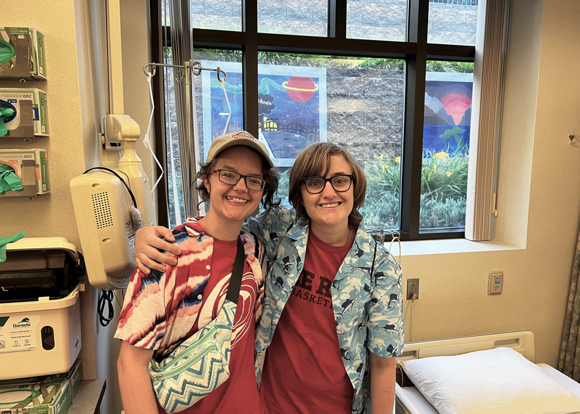 Two people smiling in front of a window