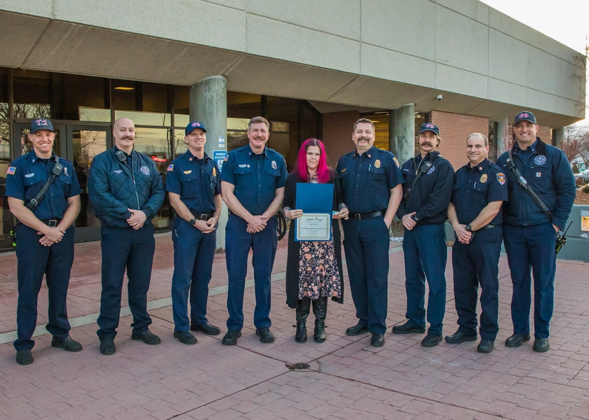 Woman with pink hair standing with firefighters