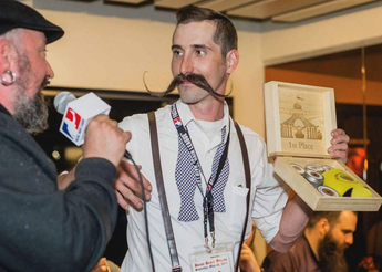 Man with suspenders and large mustache being interviewed