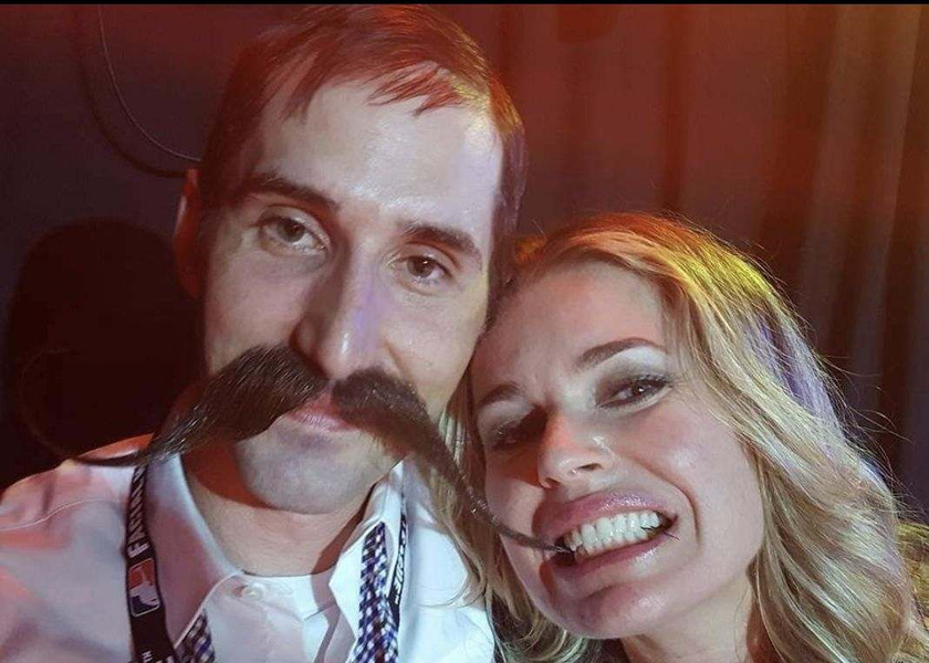 Man with large mustache and blonde woman smile at camera