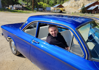 Young man in passenger side of blue car