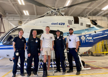 Man on crutches stands outside helicopter