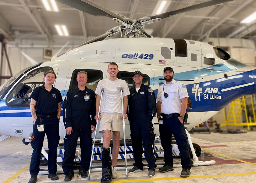 Man on crutches stands outside helicopter