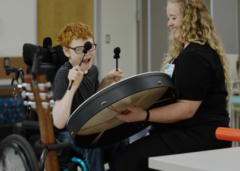 Kathrine Lee and her patient playing on a drum.