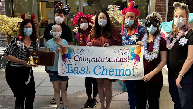 Group of people holding last chemo sign to help cheer on patient. 